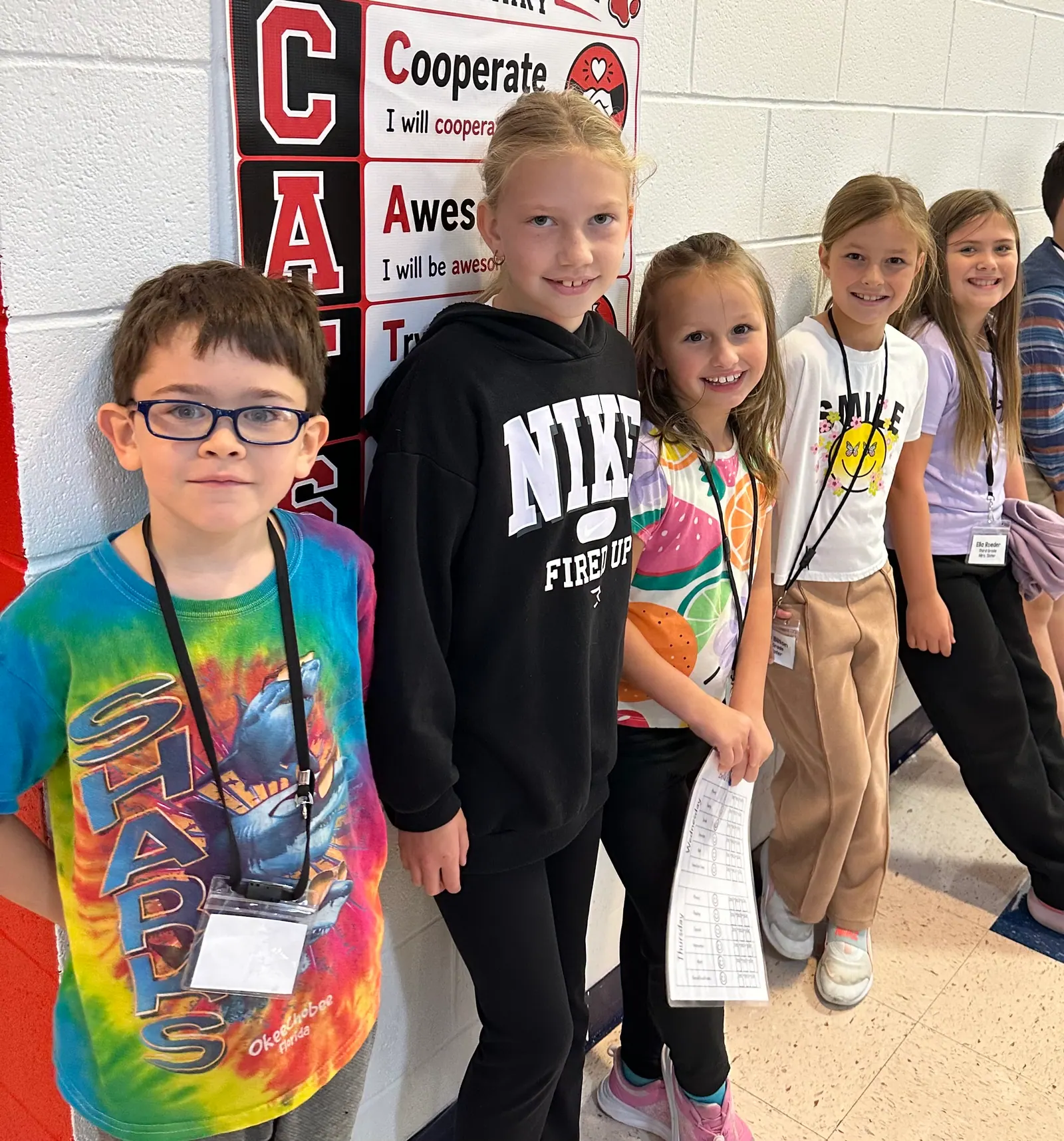 Christian Character Academy students smiling together beside a classroom character-values poster